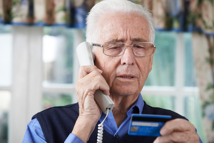 Senior Man Giving Credit Card Details On The Phone to a Scammer. Louisiana Farm Bureau Insurance will not ask for his credit card number.