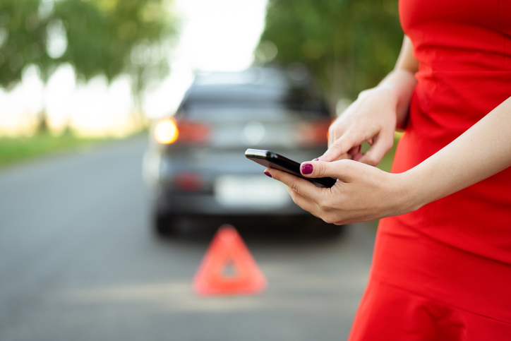 Woman needs help with her broken car and is calling on mobile phone to tow truck service.